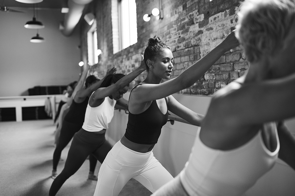 Group of women in a barre studio, unlocking the benefits of stretching during class.