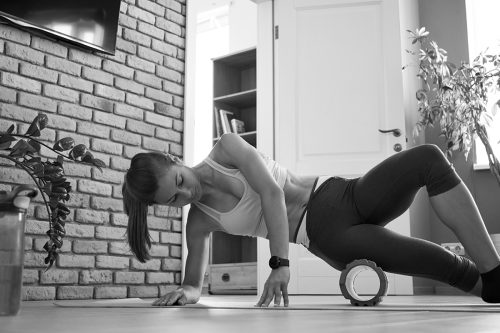 Individual using a foam roller on a yoga mat in a gym after a serratus anterior workout, focusing on muscle recovery and relaxation. 