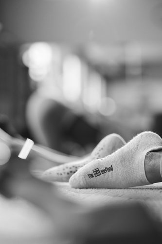 The Bar Method grippy socks on the feet of a barre class student doing exercises.

