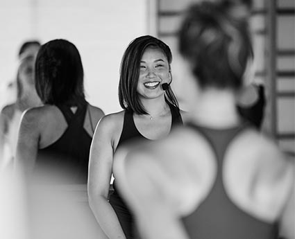 A Bar Method instructor smiling and leading a barre class.