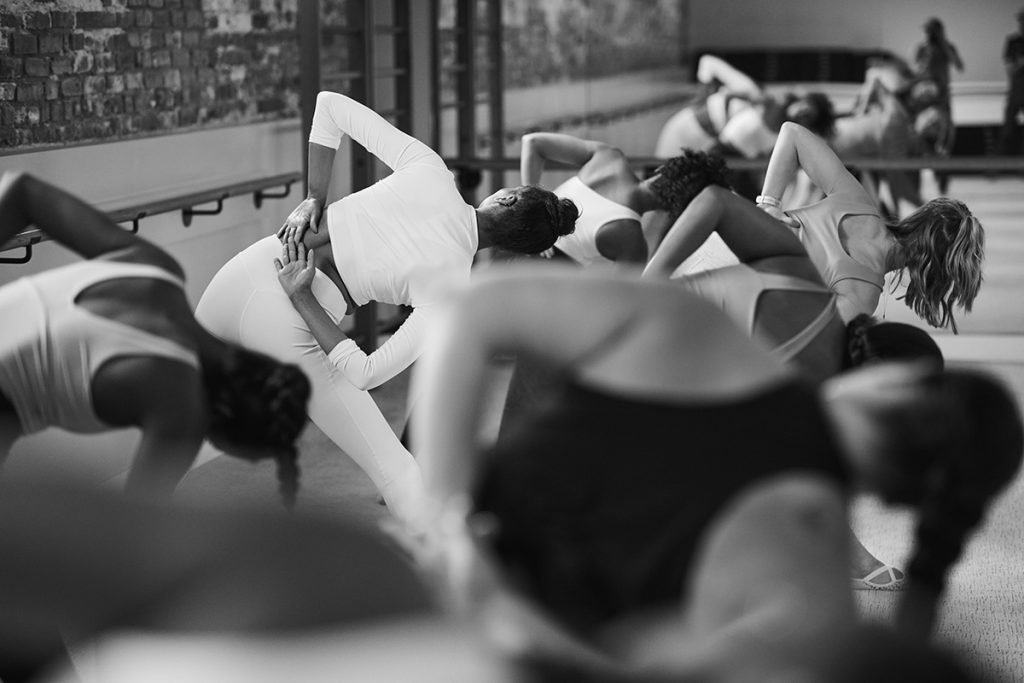 Group of women in a Bar Method studio performing low-impact exercise.