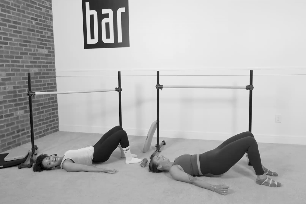 Two women in a Bar Method studio performing back dancing, one of the stability exercises featured in the Bar Method.
