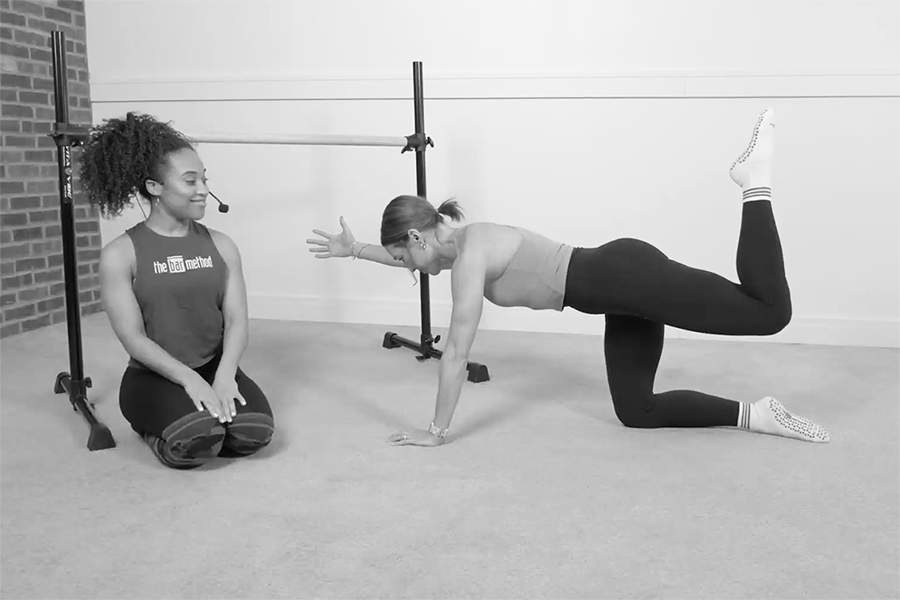 Bar Method instructor teaching a member how to do floor zingers with opposite arms extended, one of the stability exercises found in The Bar Method.