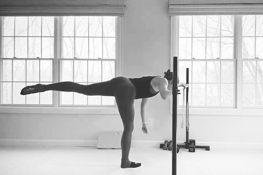 Woman in a barre studio demonstrating a foldover deadlift, one of the stability exercises featured in The Bar Method.