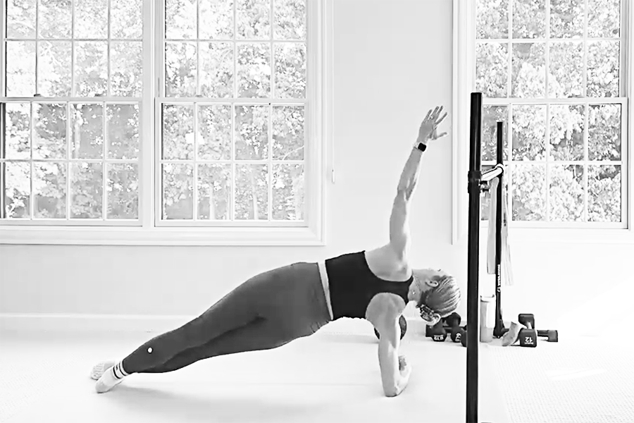 Woman in a barre studio demonstrating a side plank, one of the stability exercises featured in The Bar Method.