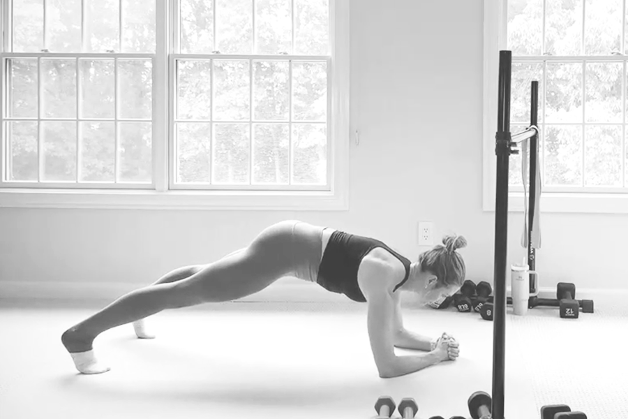 Woman in a barre studio demonstrating a walking plank, one of the stability exercises featured in The Bar Method.