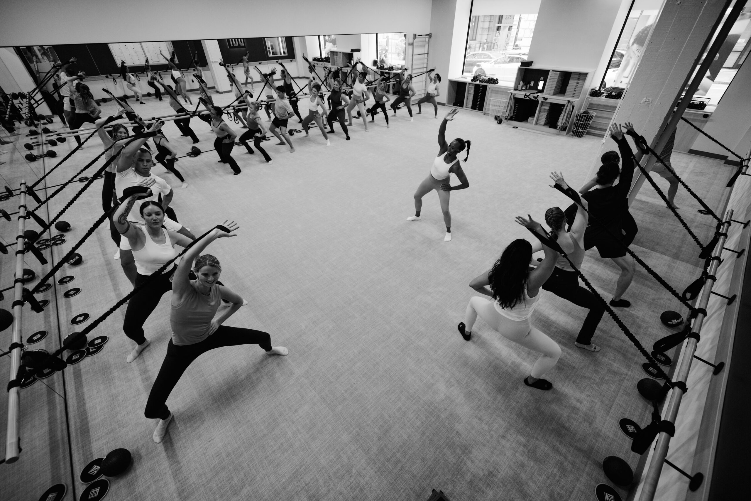 Black and white image of woman smiling and resting her head on the Barre after completing a workout