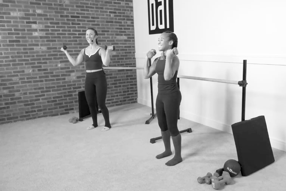 Bar Method instructor demonstrating bicep curls, part of a barre back workout.