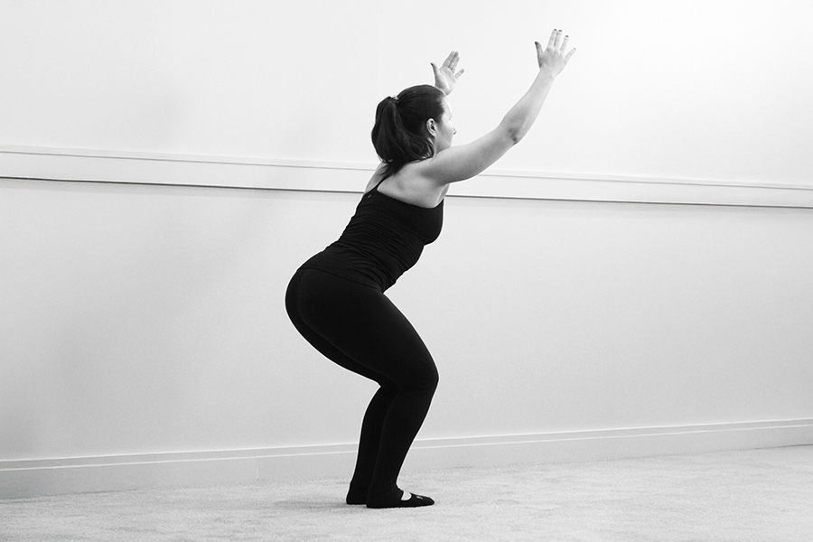 Bar Method instructor demonstrating chair, part of a barre back workout.