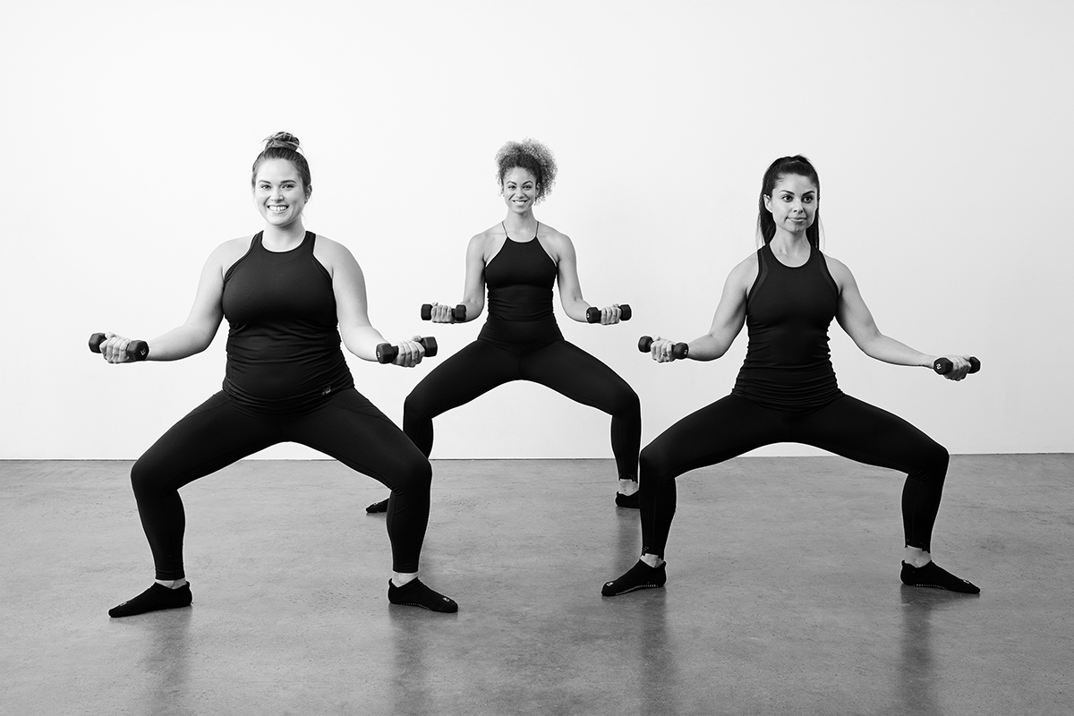 Three women in barre gear demonstrating second position thigh, part of a prenatal core workout.