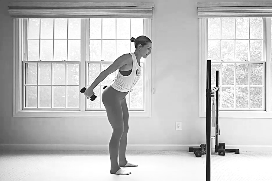 Bar Method instructor demonstrating tricep kickbacks, part of a barre back workout.